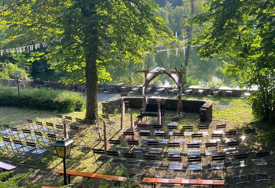 Bestuhlung im Garten des Haus am See vor einem Traubogen aus Holz für eine freie Trauung