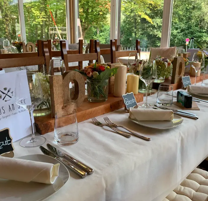 Tischkarten auf einem festlich dekorierten Tisch mit Blumenarrangement im Haus am See