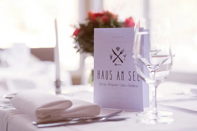 Speisekarte auf einem festlich dekorierten Tisch mit Blumen und Kerzen im Haus am See