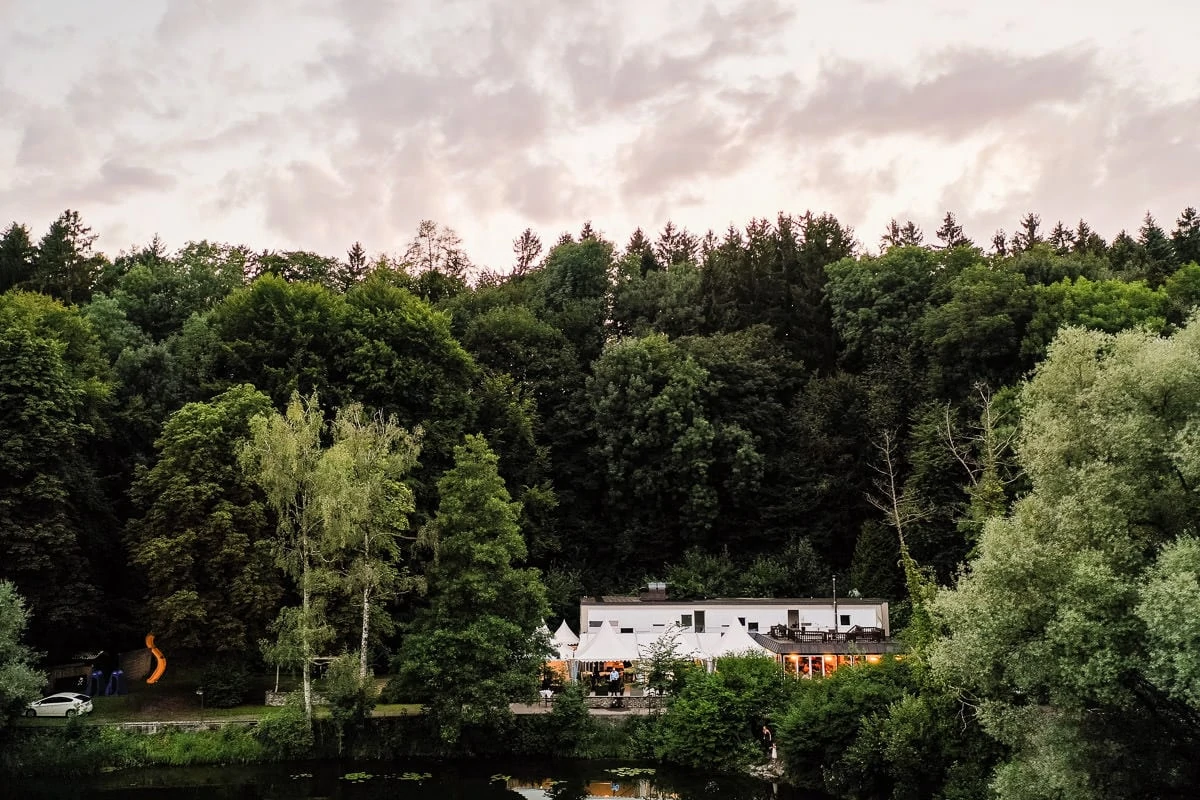 Haus am See mit Blick auf die Fassade und den umliegenden Wald im Hintergrund